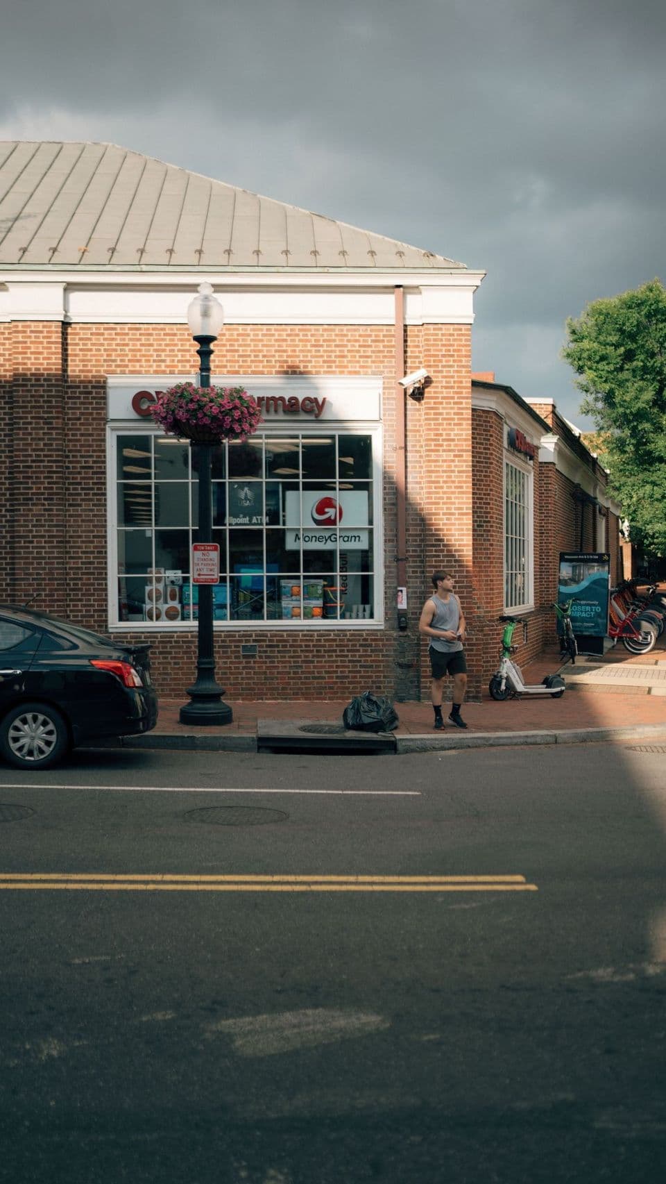 A small-town brick pharmacy storefront on a quiet main street.